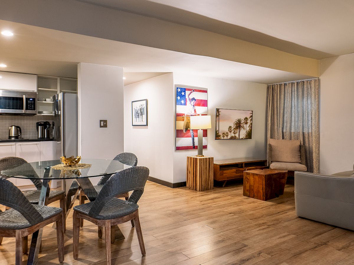 Bright open-plan living/dining area with a modern kitchen, sofa seating, coffee table, and framed wall art.